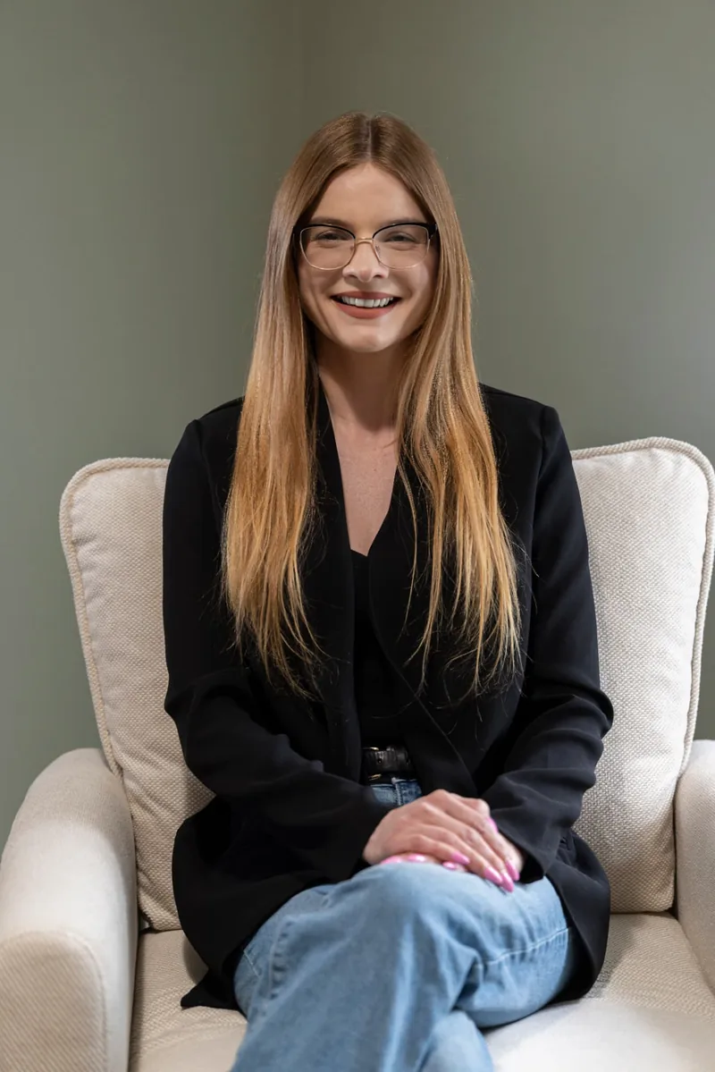 Katie Fortune, MA, LPC, NCC, a couples therapist at Shoreside Therapies in Glendale, seated in a chair and smiling.